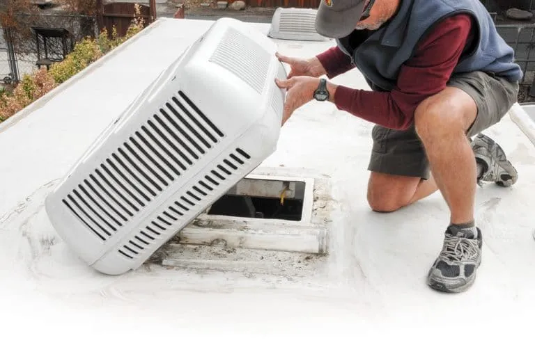 Technician repairing a rooftop RV air conditioner during a mobile visit in the East Valley