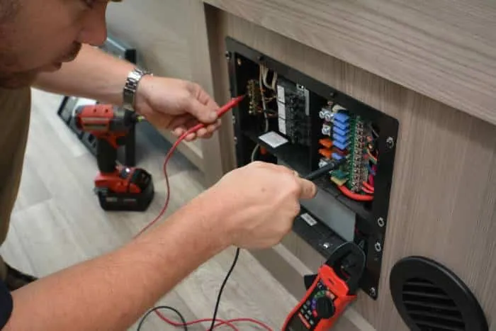 Technician troubleshooting RV electrical wiring and batteries during mobile service in the East Valley